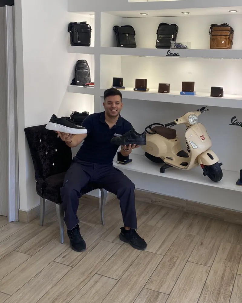 Thodoris, owner of Doctor Shoes, in the shop in Nikaia holding repaired shoes